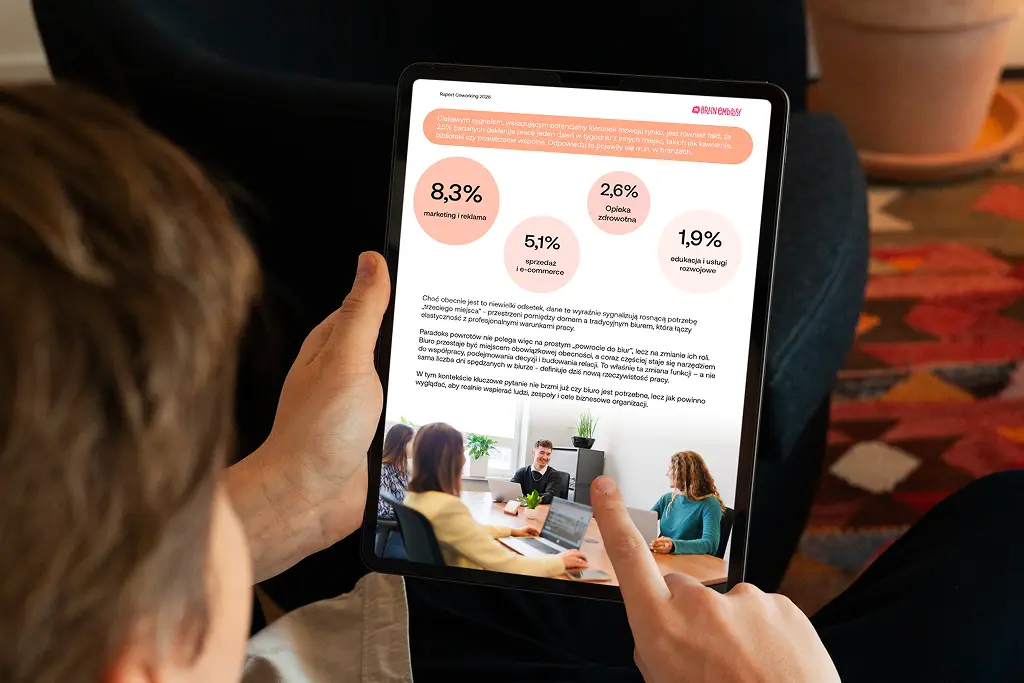 A person holding a tablet displaying the “Coworking 2026” report