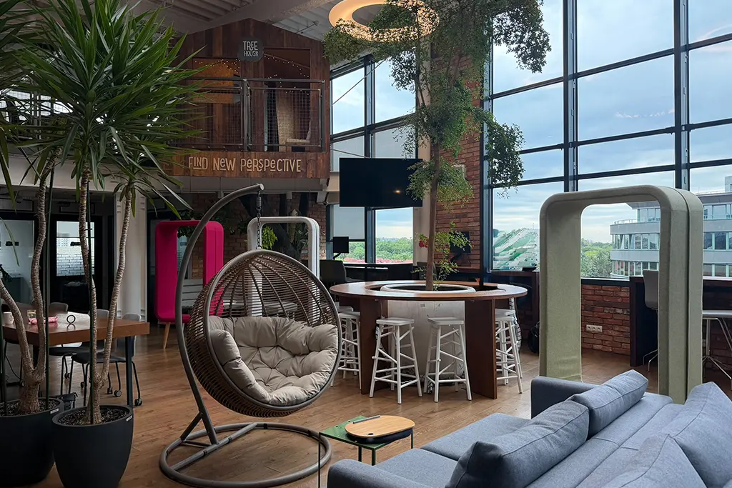 Biophilic office space featuring indoor plants, large windows and relaxation areas.